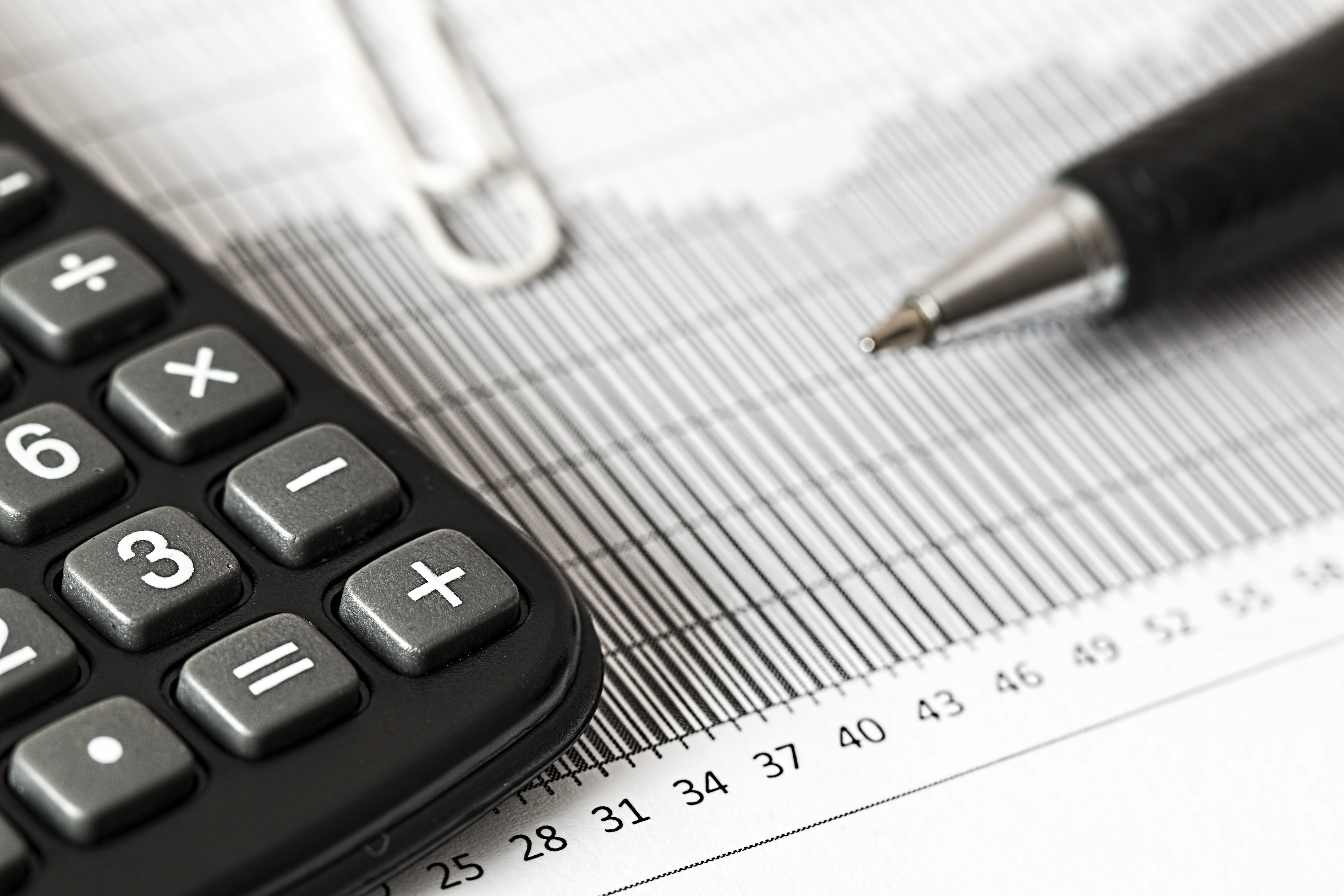 Close up shot of a calculator and a pen on top of a printed chart
