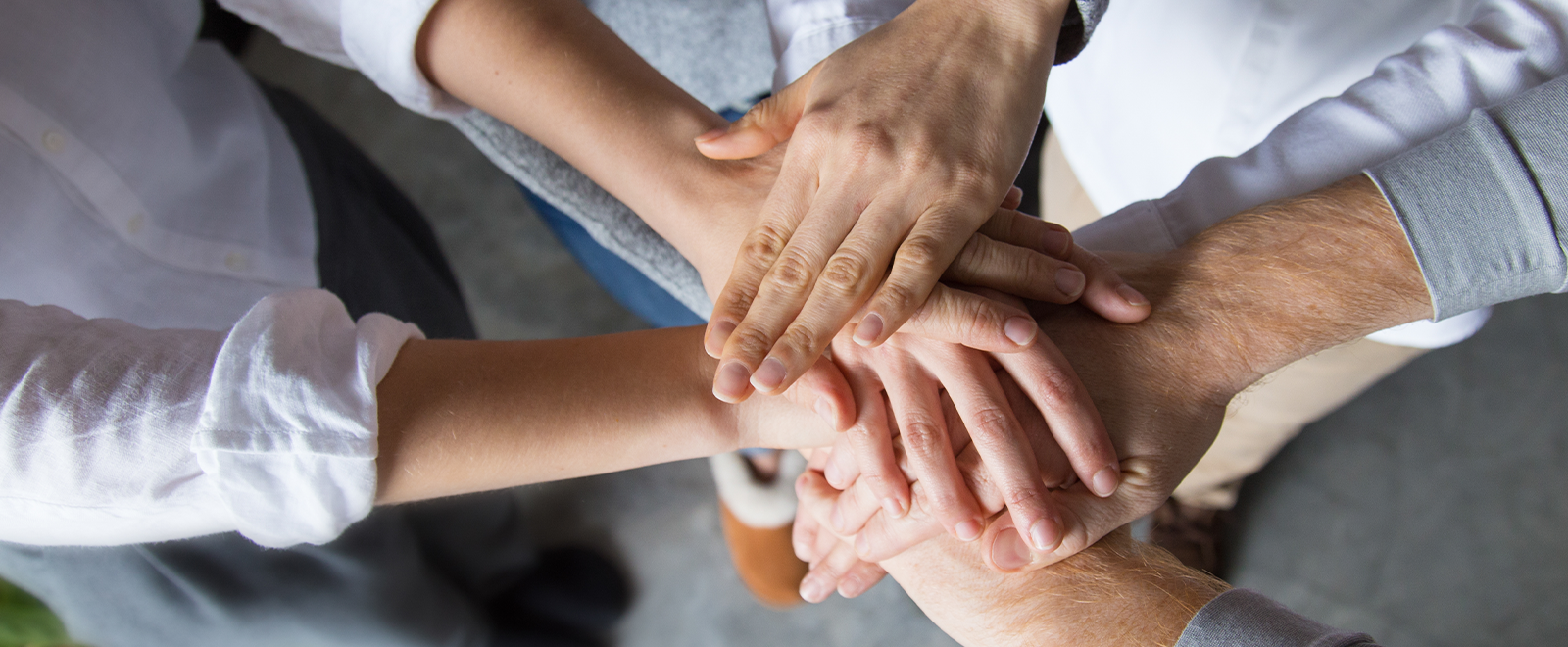 Close-up photo of a group of hands in a circle on top of each other