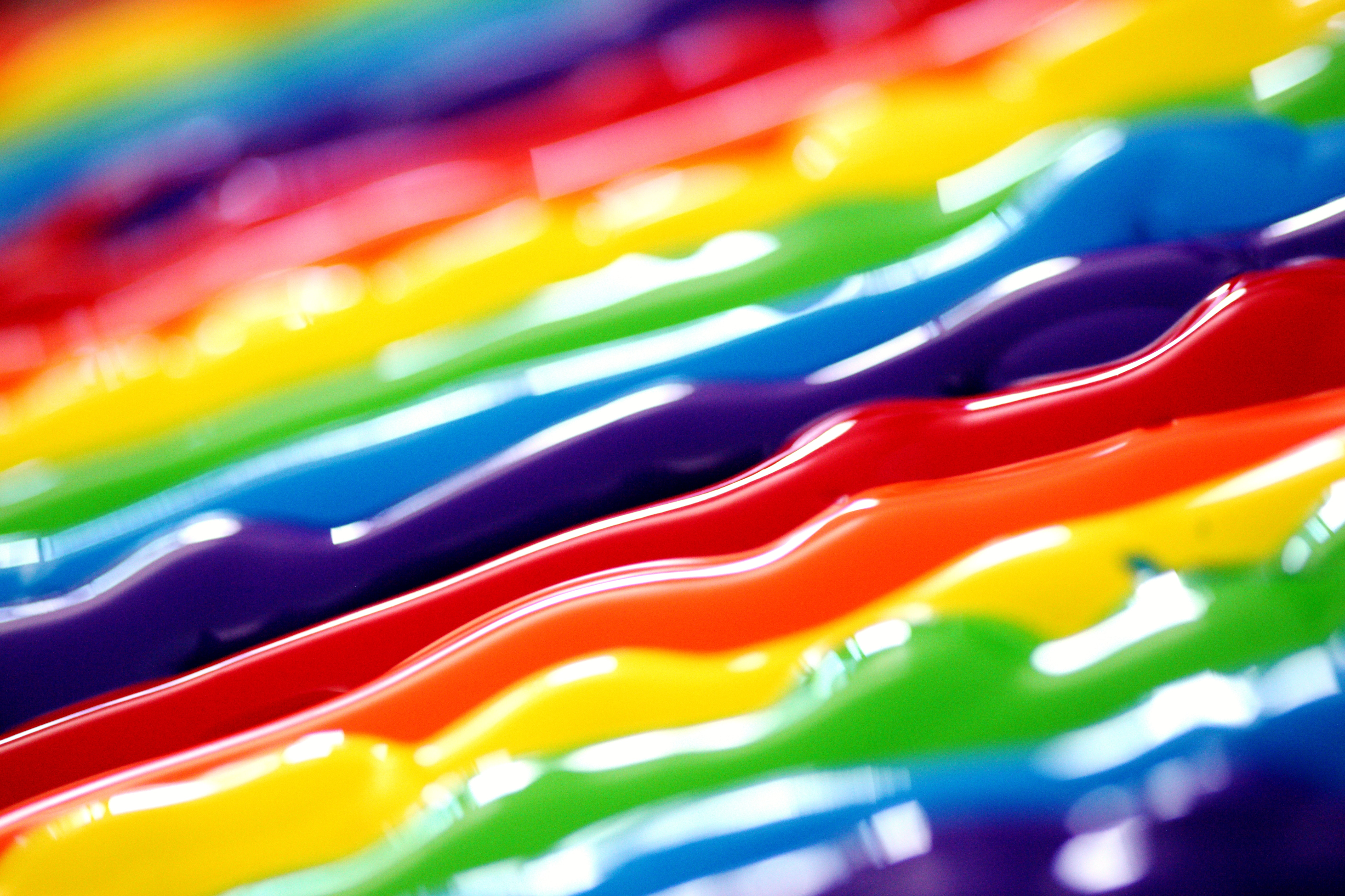 Close up of strands of paint in a rainbow of colours