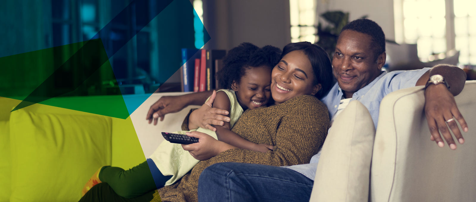 Photograph of a family of people of colour on a sofa cuddling and looking happy