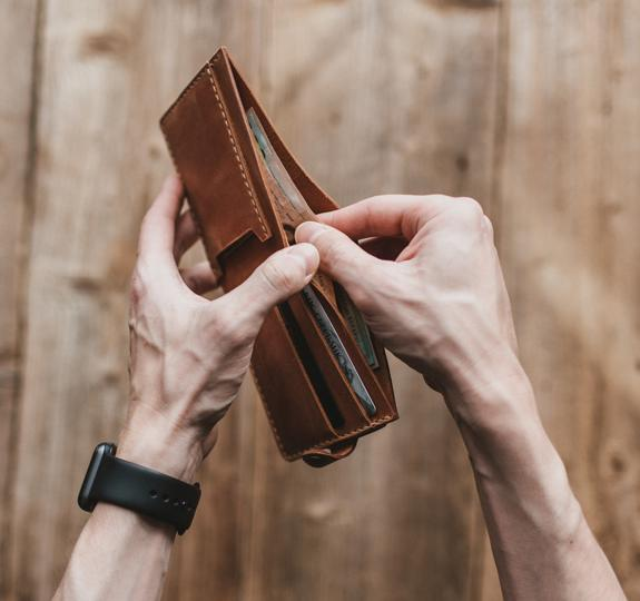 Close up photograph of someone about to remove a banknote from a wallet