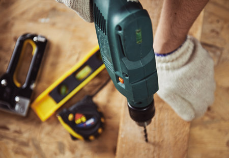 Photograph of someone drilling into a piece of wood with other tools in the background