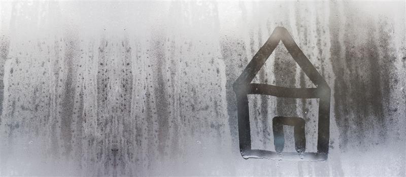 Photograph of condensation on a window. There is a simple image of a house drawn into it. 