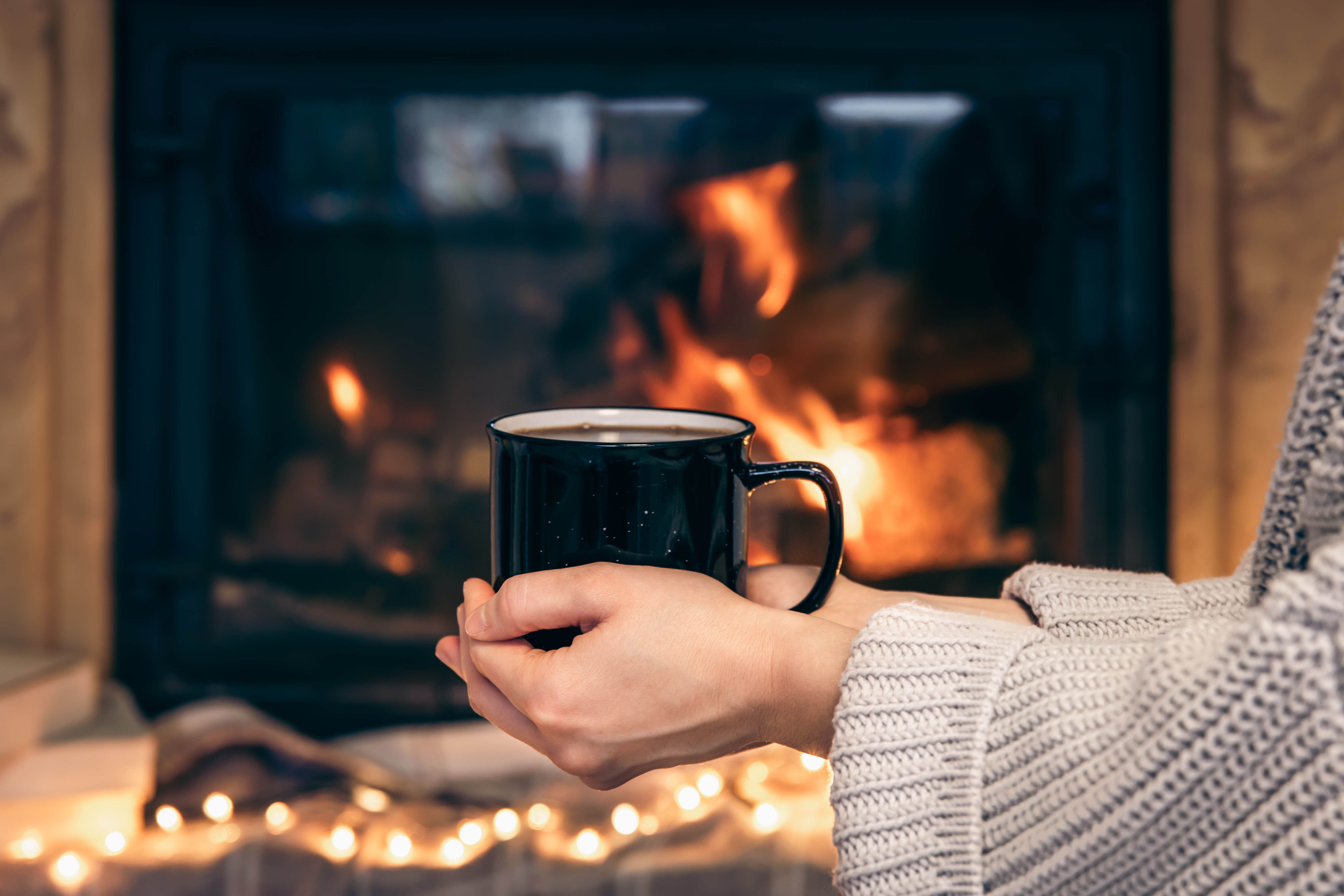 Cup With Hot Drink Female Hands Blurred Fireplace Background