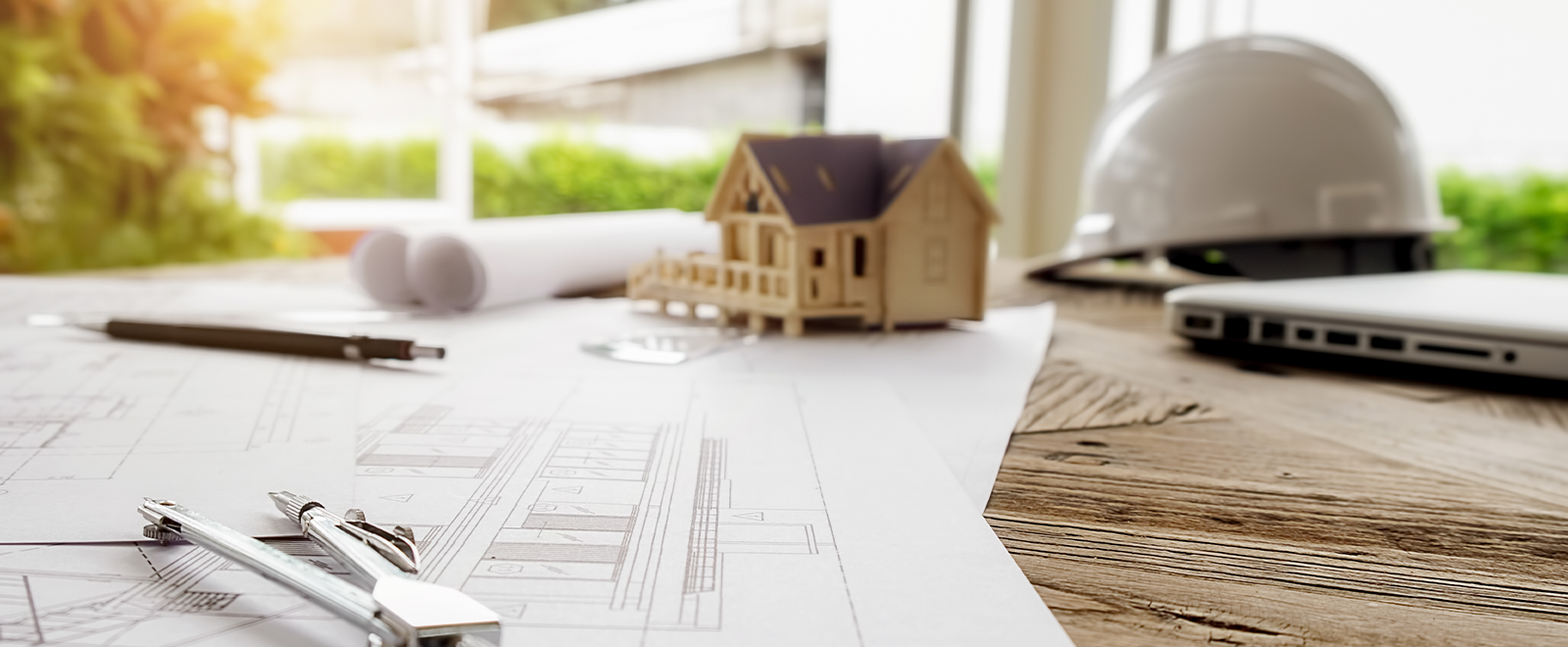 Photo of a small wooden model house on top of a table with sheets of paper