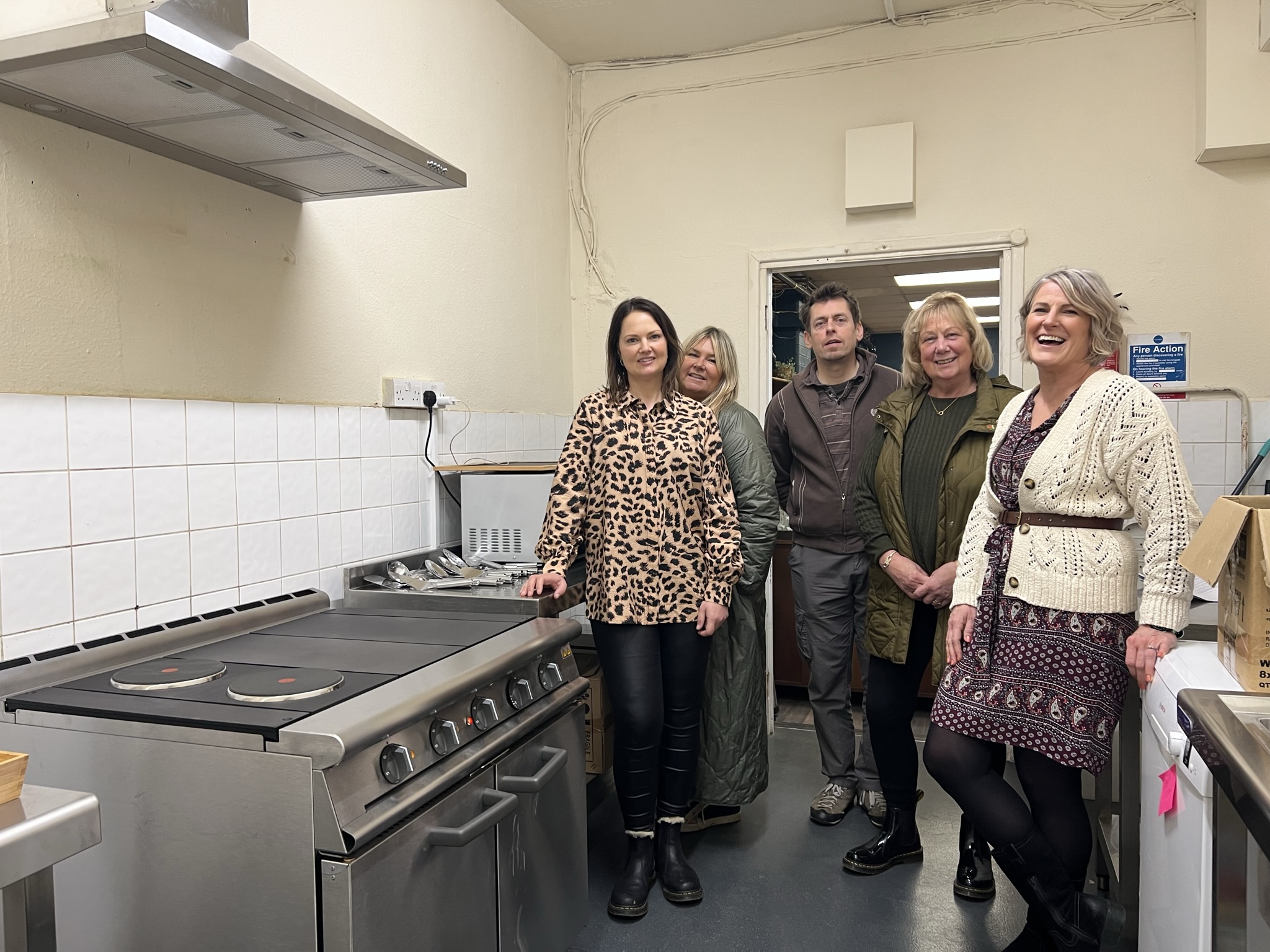 Photo of several people in the kitchen at the Salcare charity looking at the newly-installed cooker