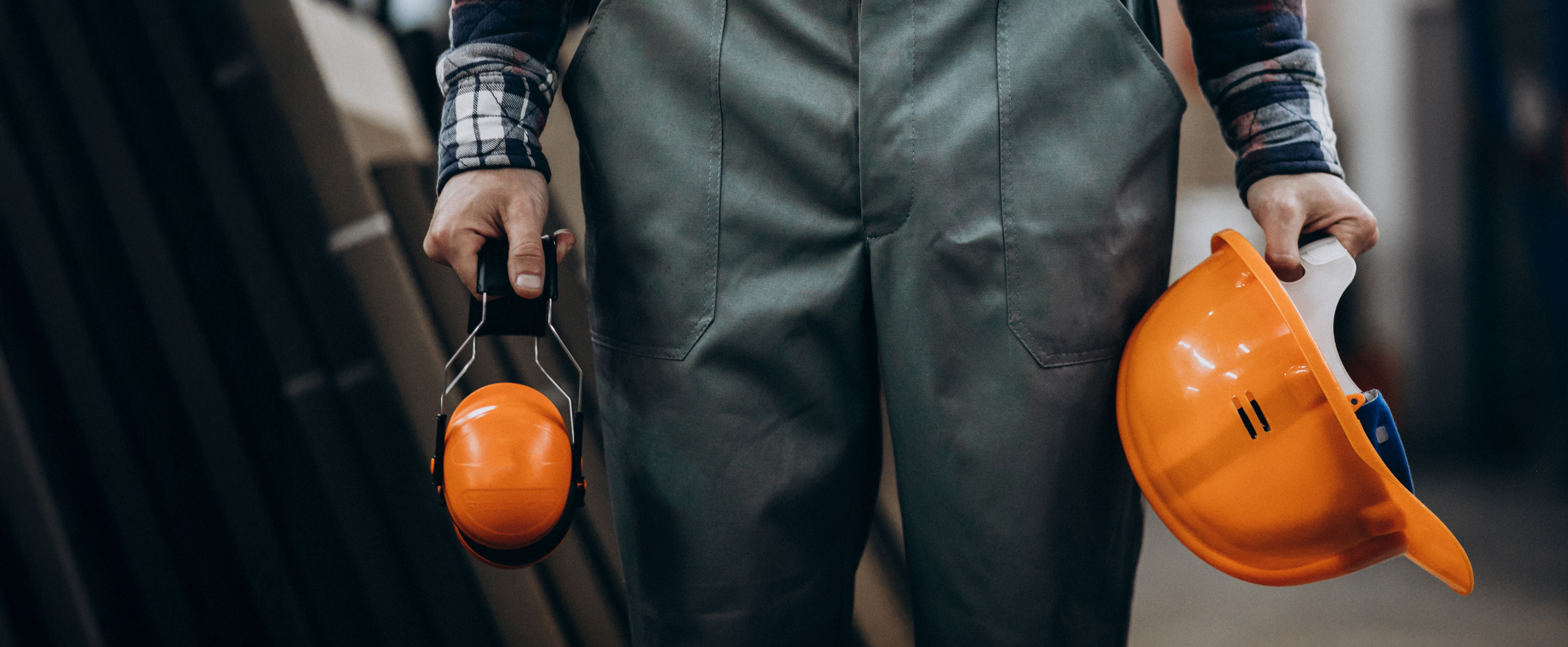 Construction worker holding safety earphones and helmet