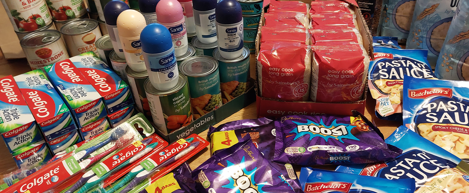 Photo of a table full of food and toiletries items, tins, chocolate, toothpaste etc