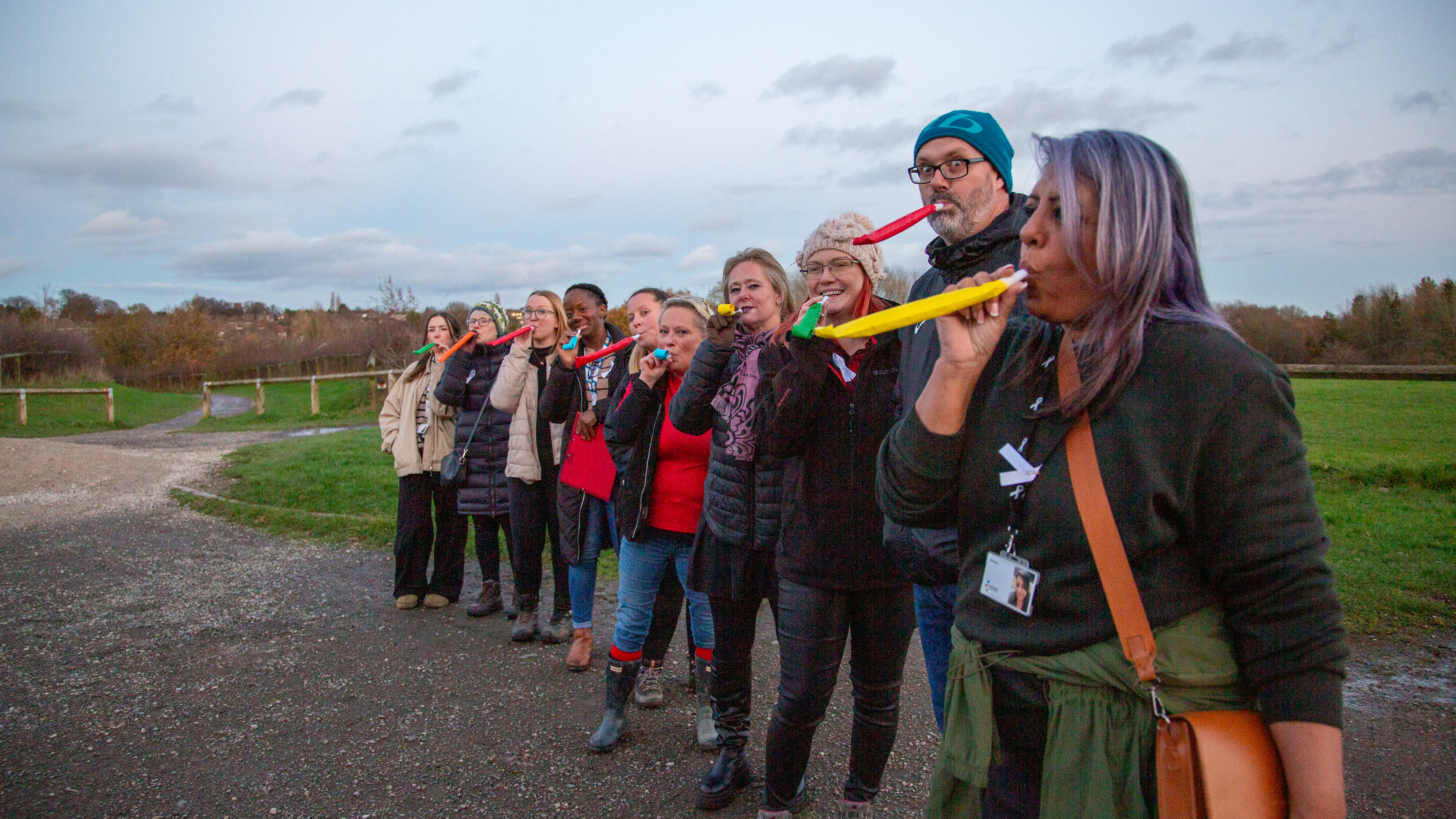 Group of people outside with party blowers in their mouths