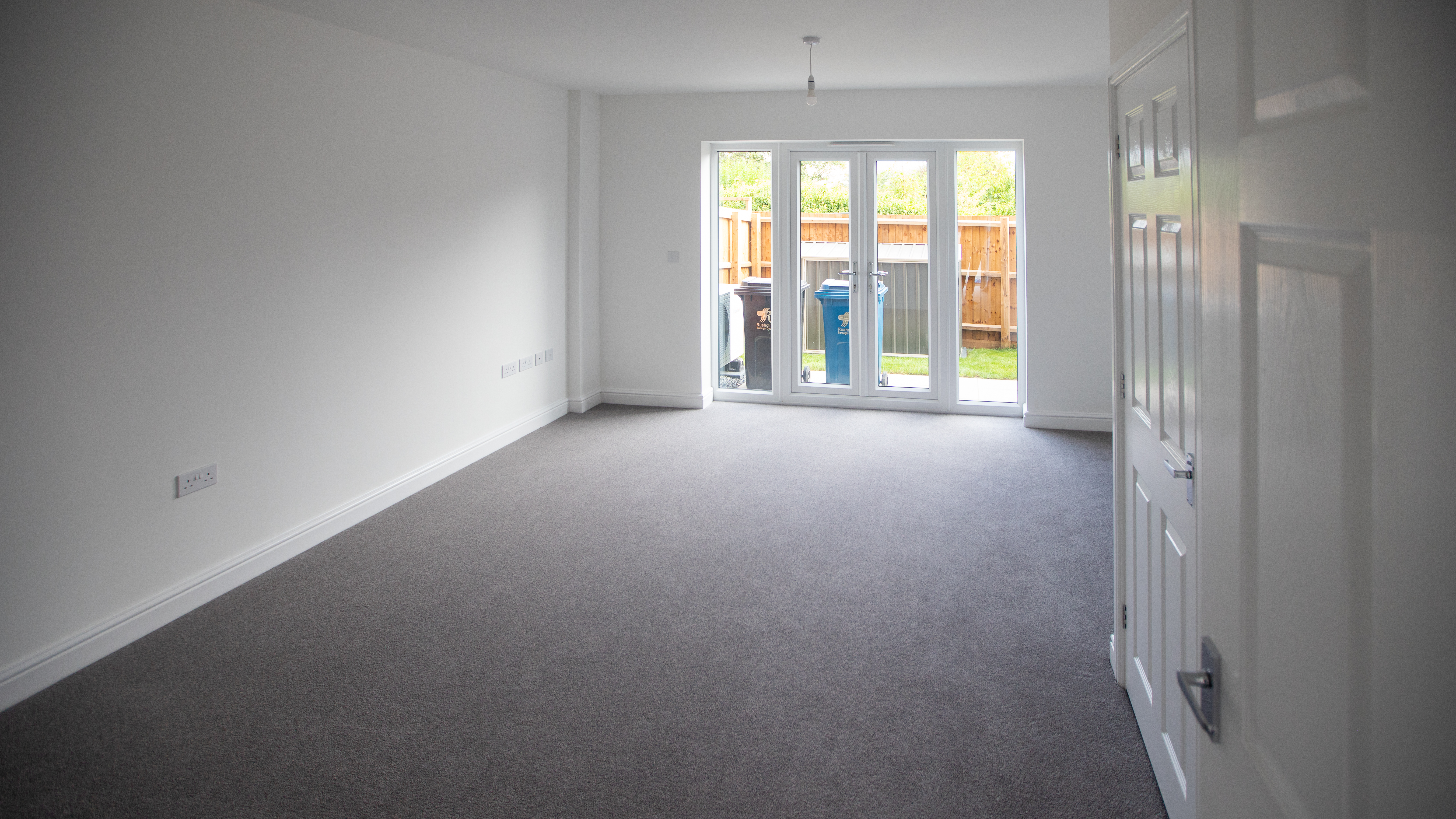 Photo of a plain white living room with french doors looking into garden