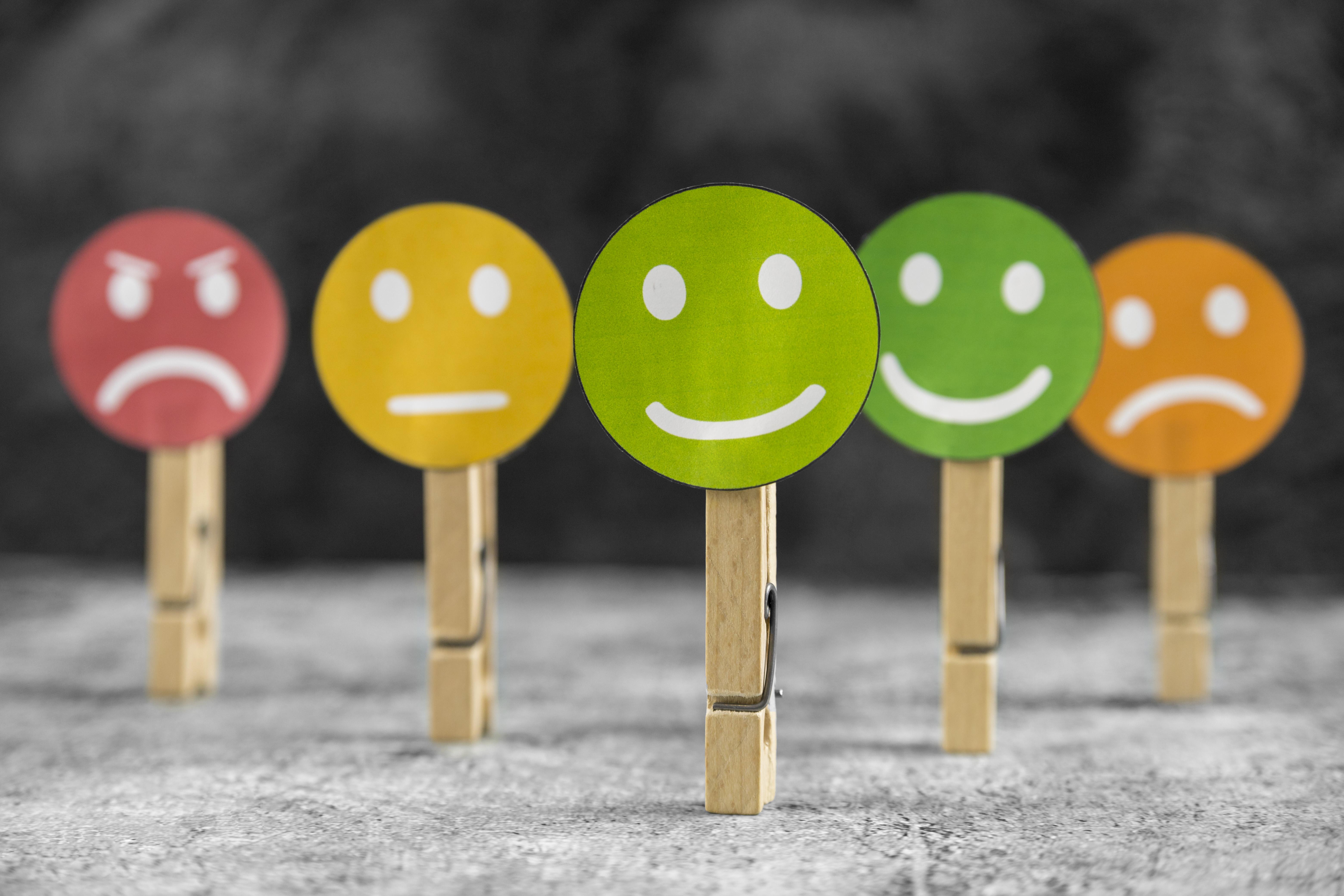 Five faces with different emotions on wooden pegs