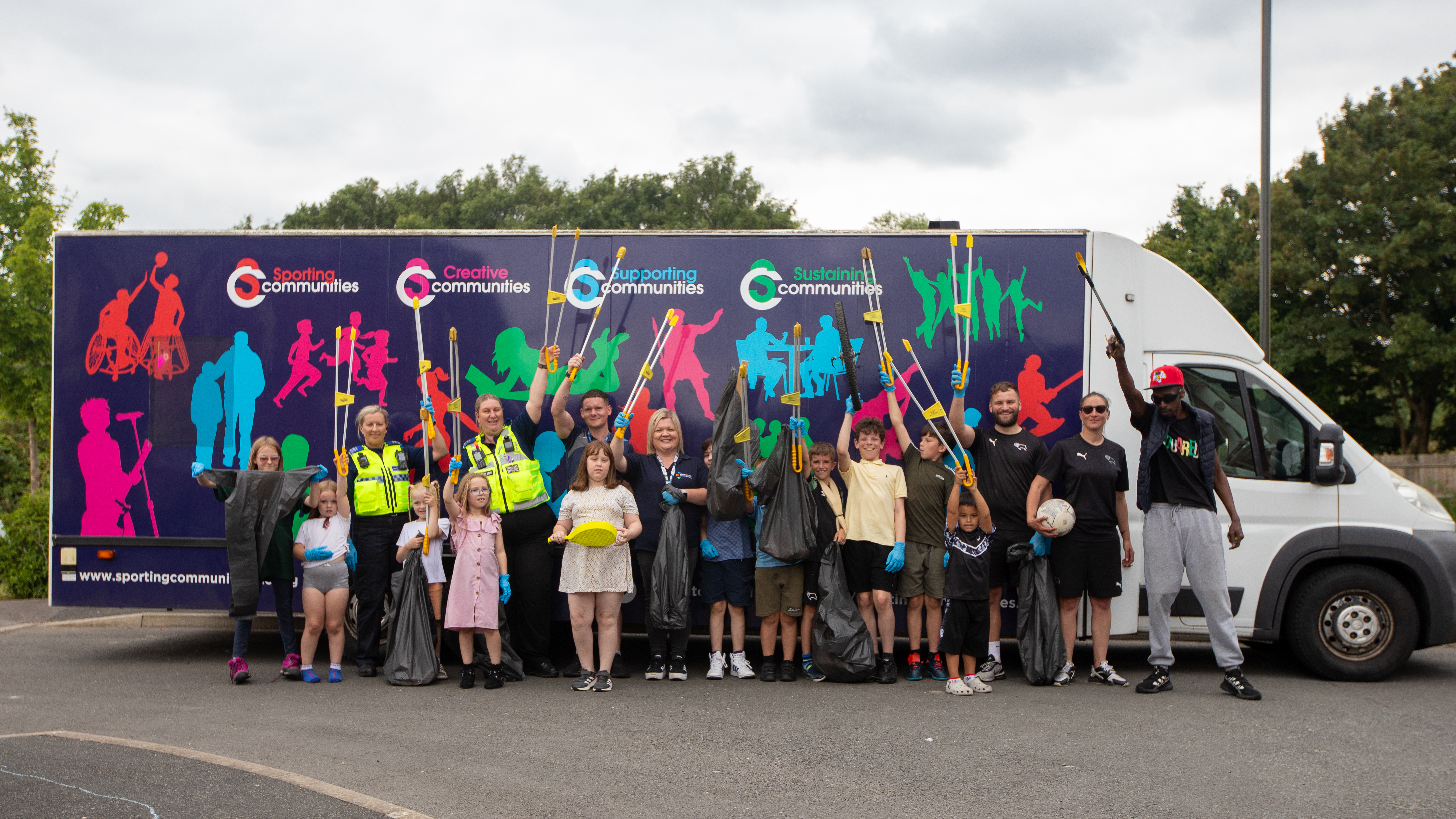 Group of partners and children with litter pickers and sports equipment