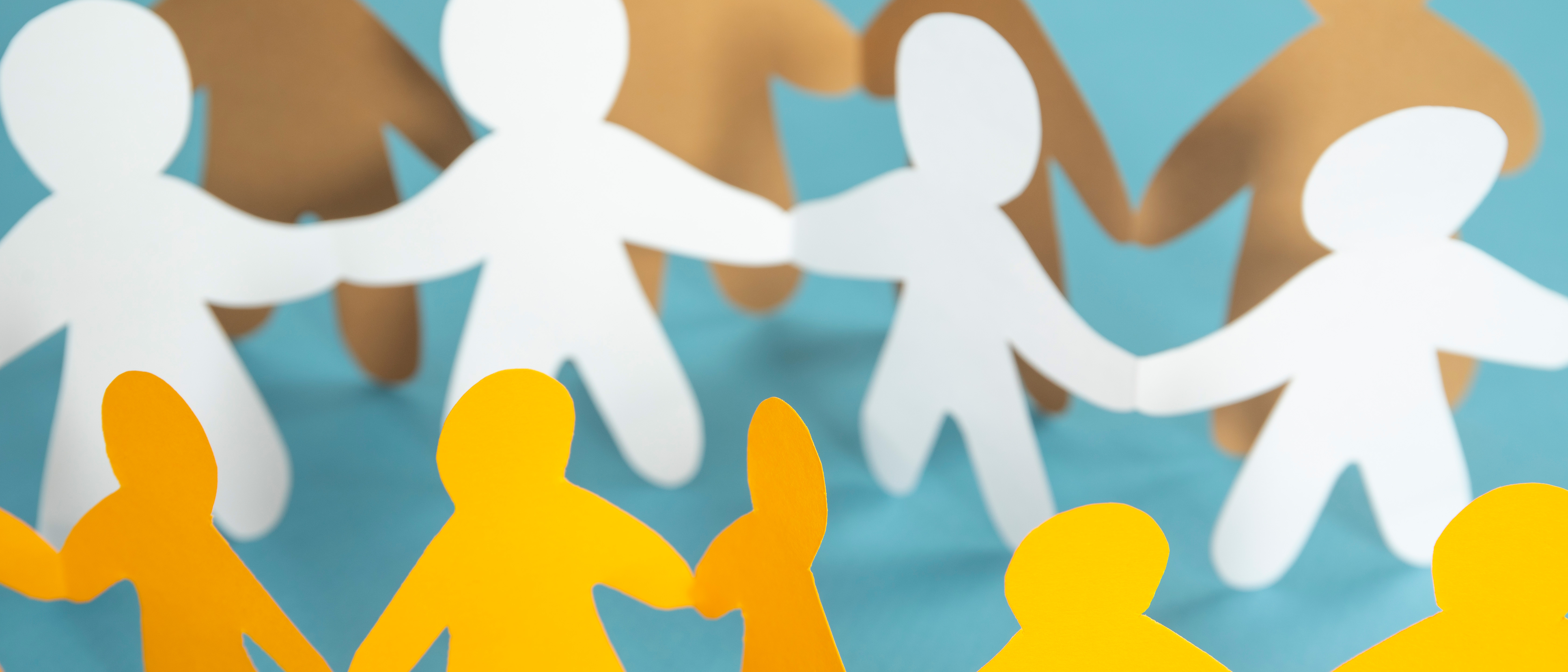 Simple white and yellow paperchain cut-outs of people holding hands arranged in alternating rows of yellow and white