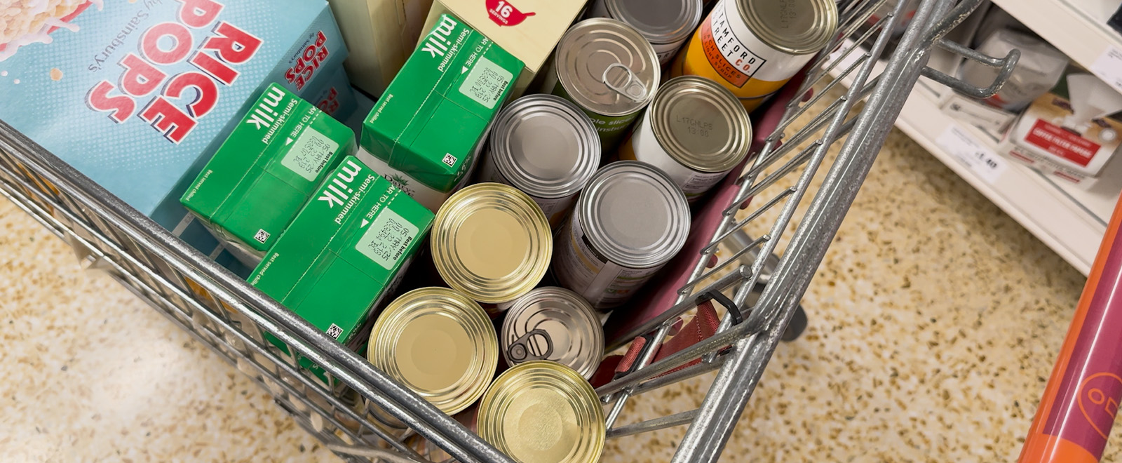 Shopping trolley with tinned items, cartons of milk and cereal
