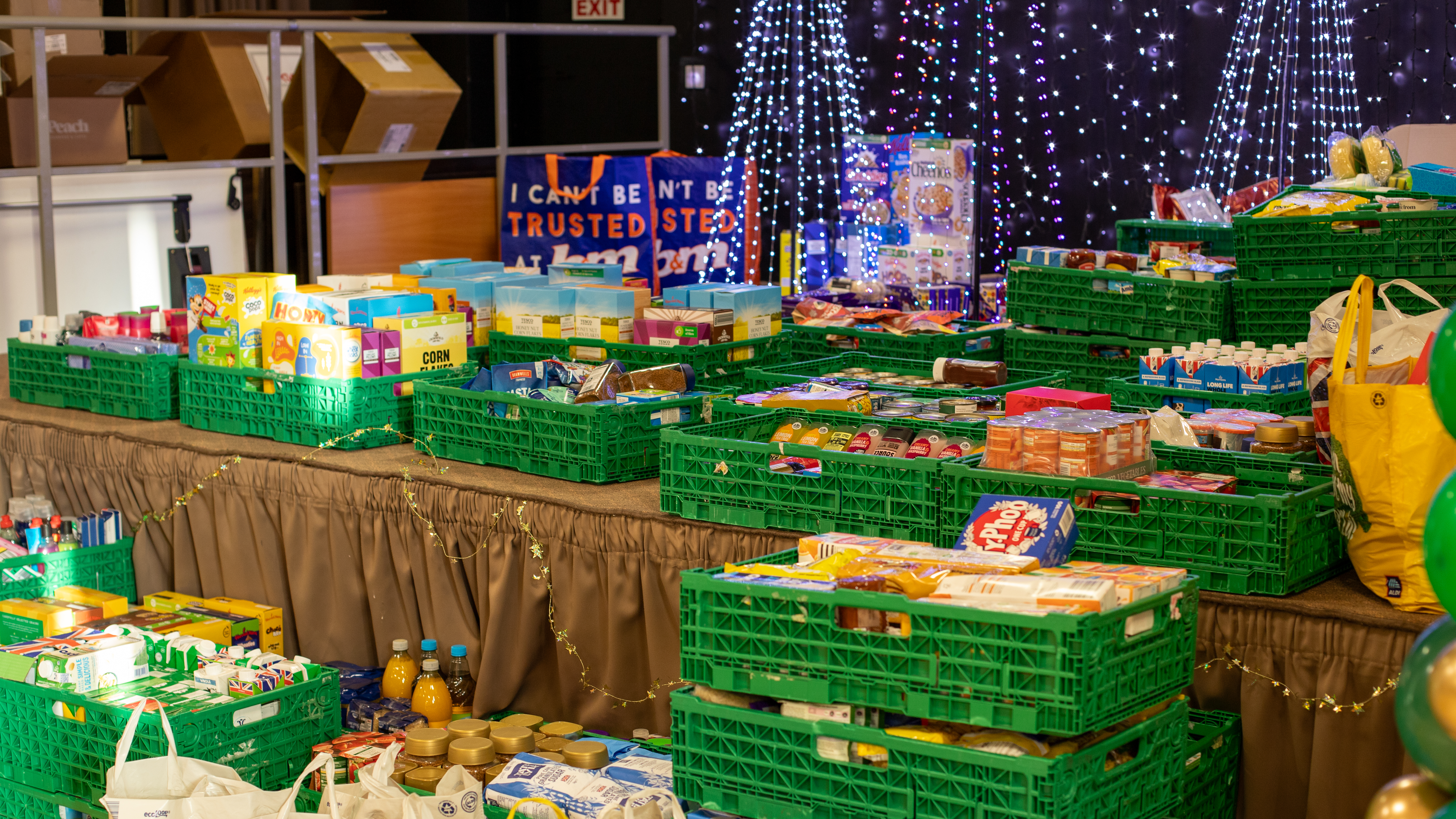 Crates of food on a stage with Christmas decorations in the background