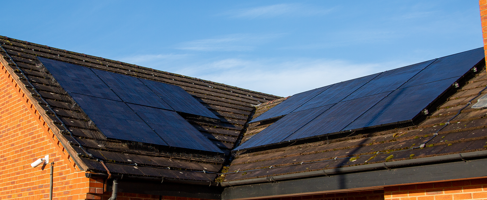 Photo of solar panels on top of a roof, blue sky